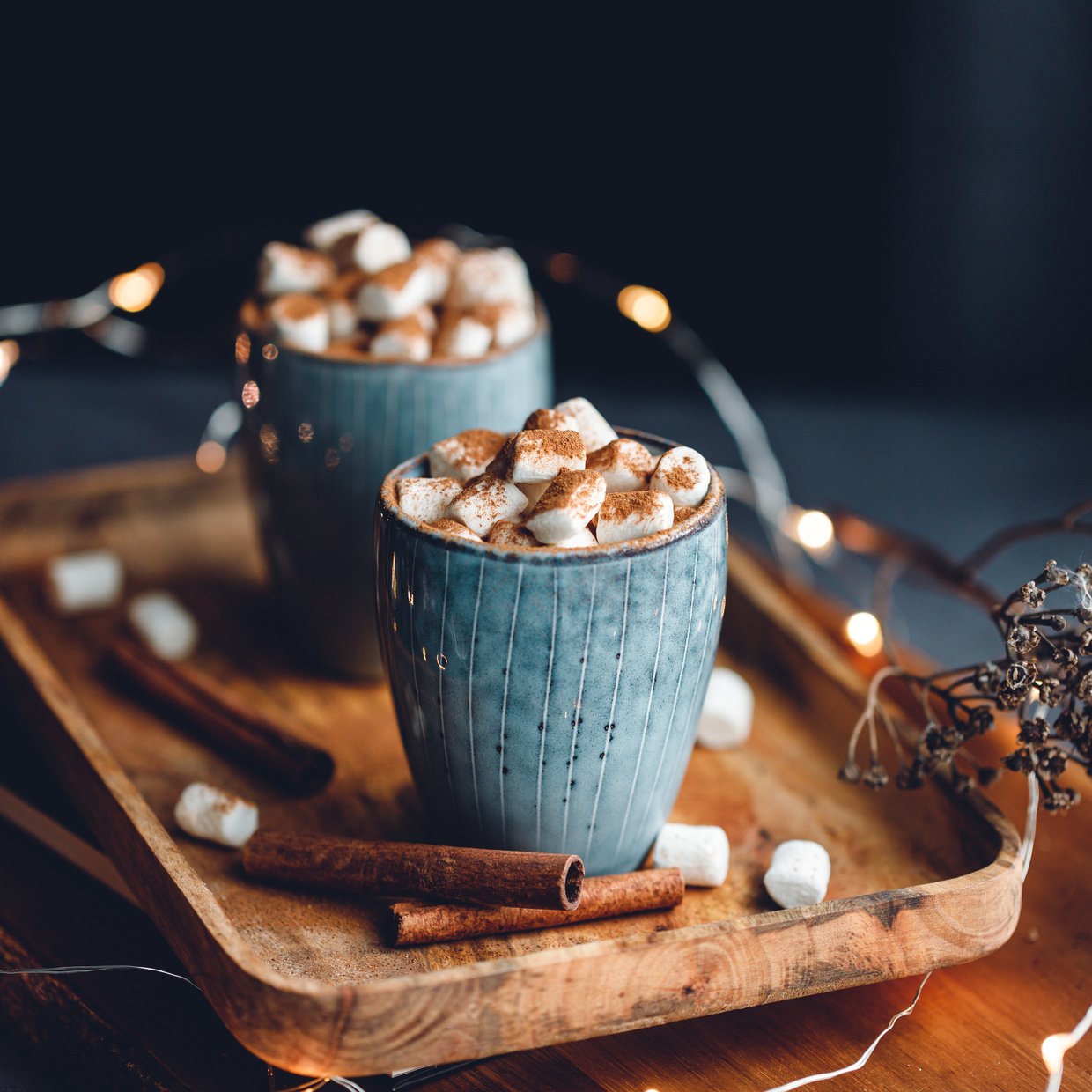 Hot chocolate with marshmallow and cinnamon in a blue ceramic cups on a table. The concept of cosy holidays and New Year.